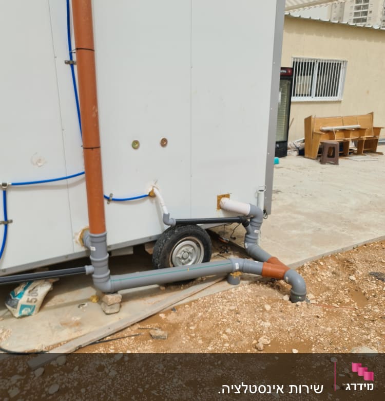 צינורות פלסטיק חומים ואפורים מחוברים לקיר חיצוני